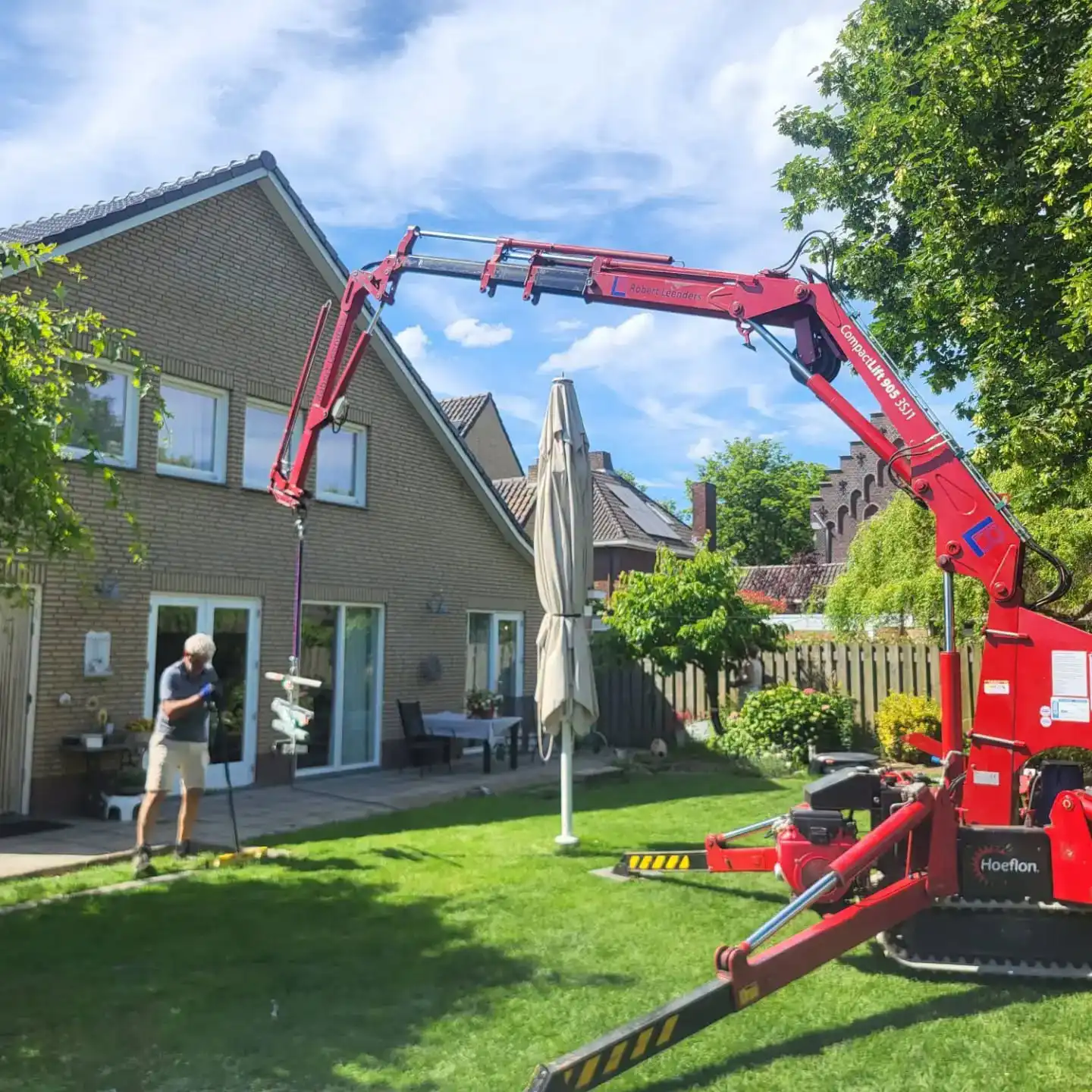 Onze compacte Moeflon hijskraan is in positie gebracht in een tuin.