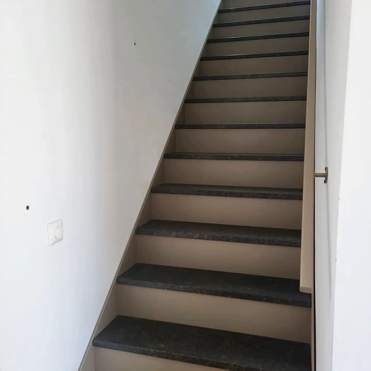 Vooraanzicht van de stalen steektrap met rechts de muurleuning.