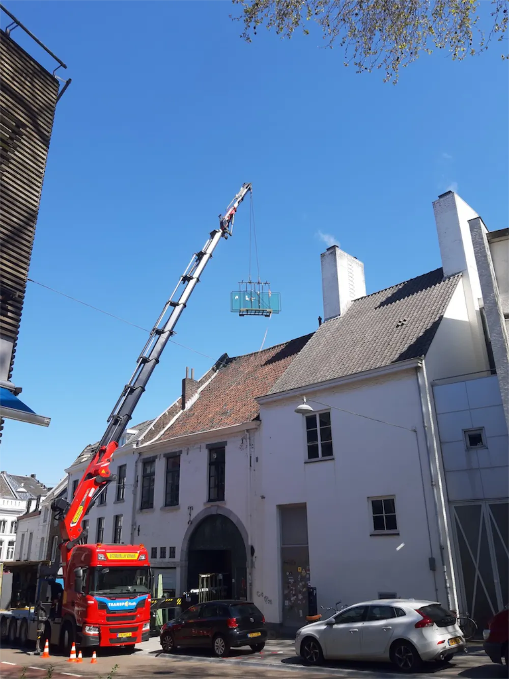 werk in uitvoering: hijskraan tilt glaspanelen over dak woonhuis